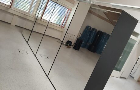 Grosser, schwarz gerahmter Spiegel in einem leeren, hellen Raum