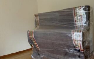 Klavier mit Decken und Stretchfolie verpackt Mit Umzugsdecken und Stretchfolie verpacktes Klavier